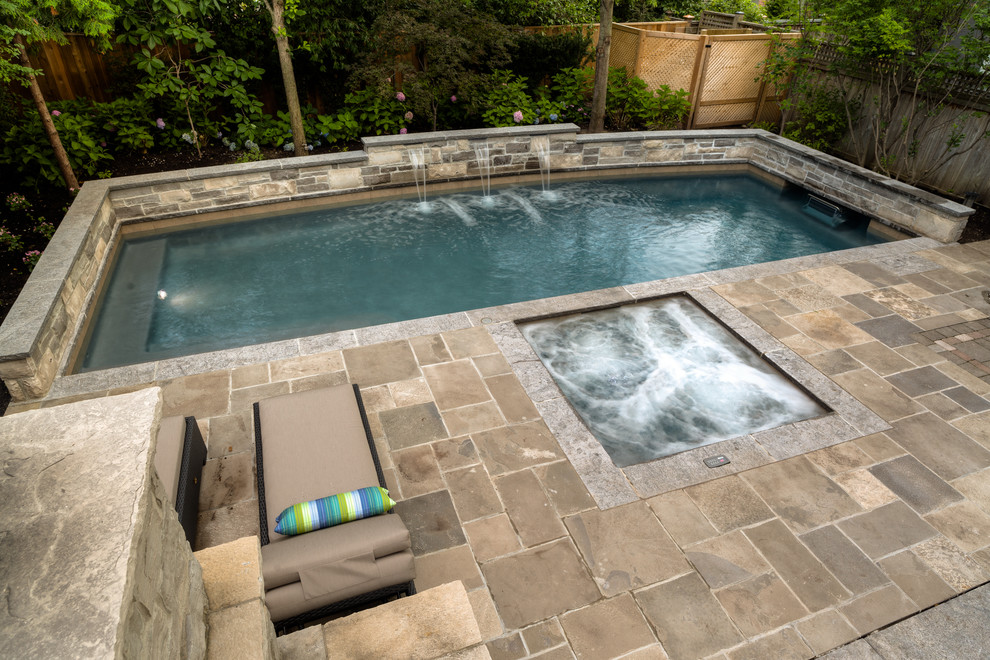 Foto di una piscina monocorsia classica rettangolare di medie dimensioni e dietro casa con fontane e pavimentazioni in pietra naturale