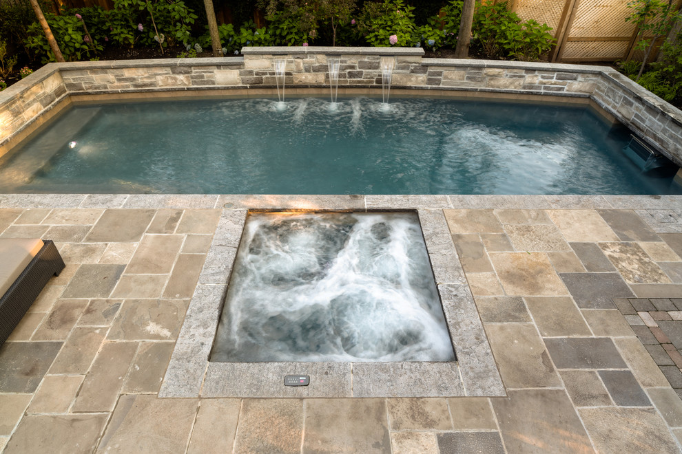 Esempio di una piscina monocorsia classica rettangolare di medie dimensioni e dietro casa con fontane e pavimentazioni in pietra naturale