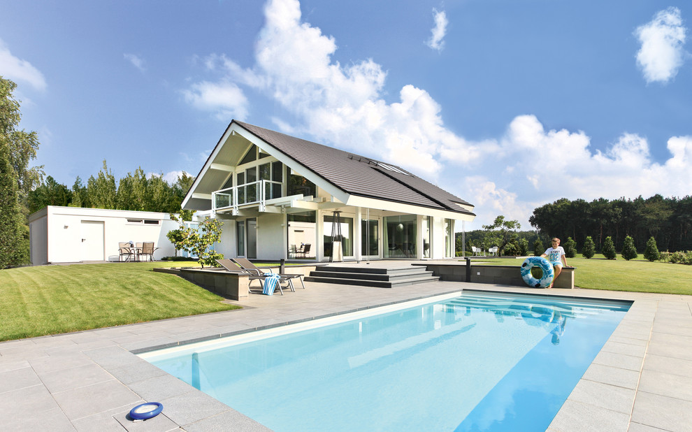 Пример оригинального дизайна: прямоугольный, спортивный бассейн среднего размера на заднем дворе в современном стиле с покрытием из плитки