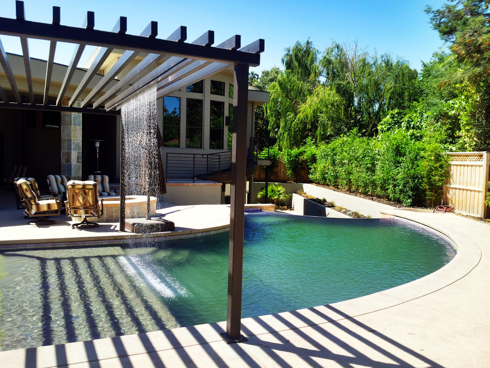 Imagen de piscina con fuente infinita mediterránea grande a medida en patio trasero con losas de hormigón