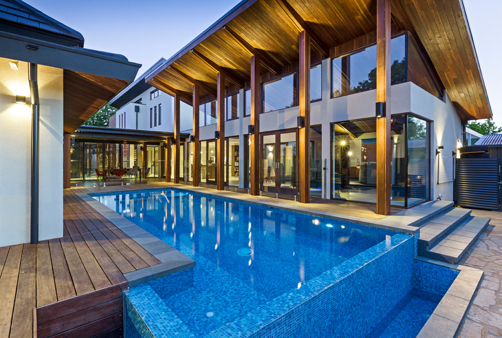 Diseño de piscina infinita contemporánea rectangular en patio con entablado