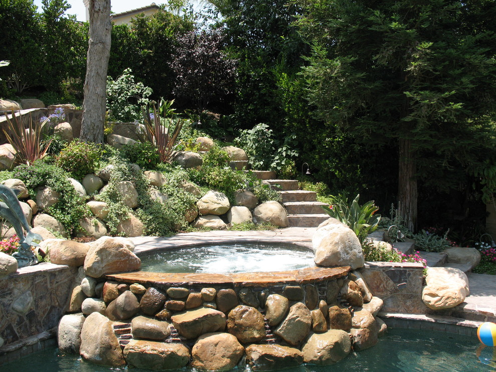 Idées déco pour une grande piscine naturelle et arrière méditerranéenne sur mesure avec un bain bouillonnant et des pavés en pierre naturelle.