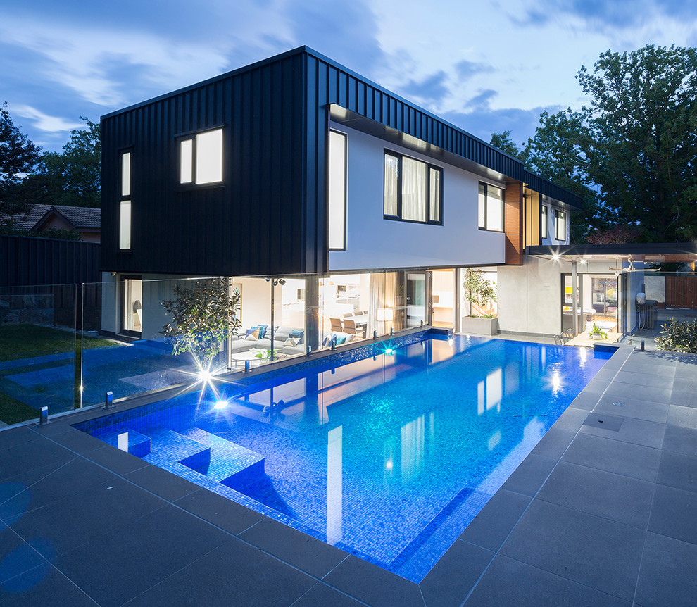 Ejemplo de piscina alargada minimalista pequeña rectangular en patio trasero con suelo de baldosas