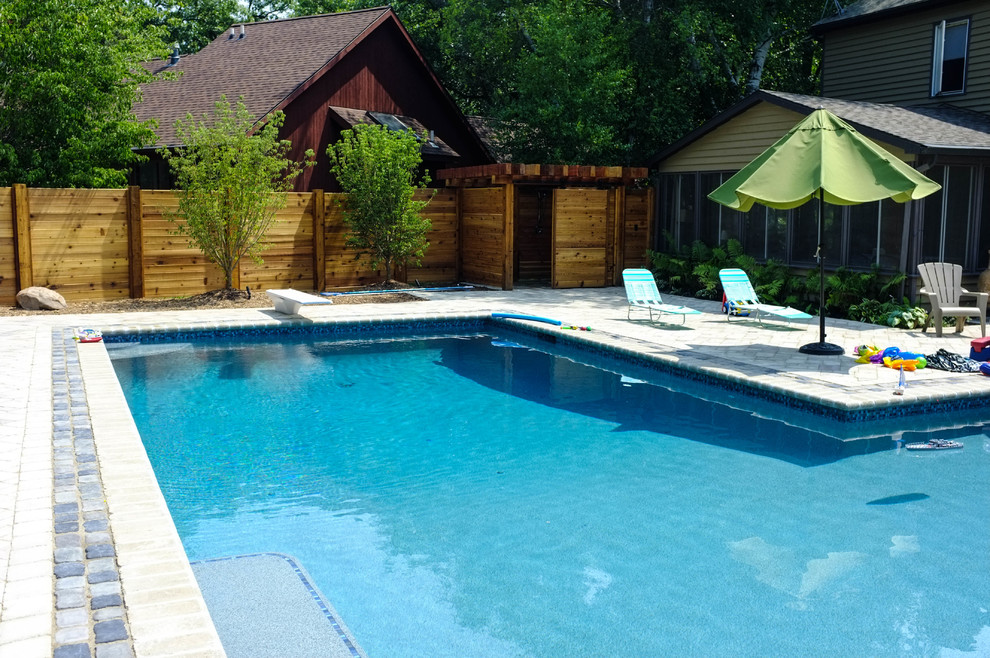 Foto de casa de la piscina y piscina natural tradicional de tamaño medio en forma de L en patio trasero con adoquines de hormigón