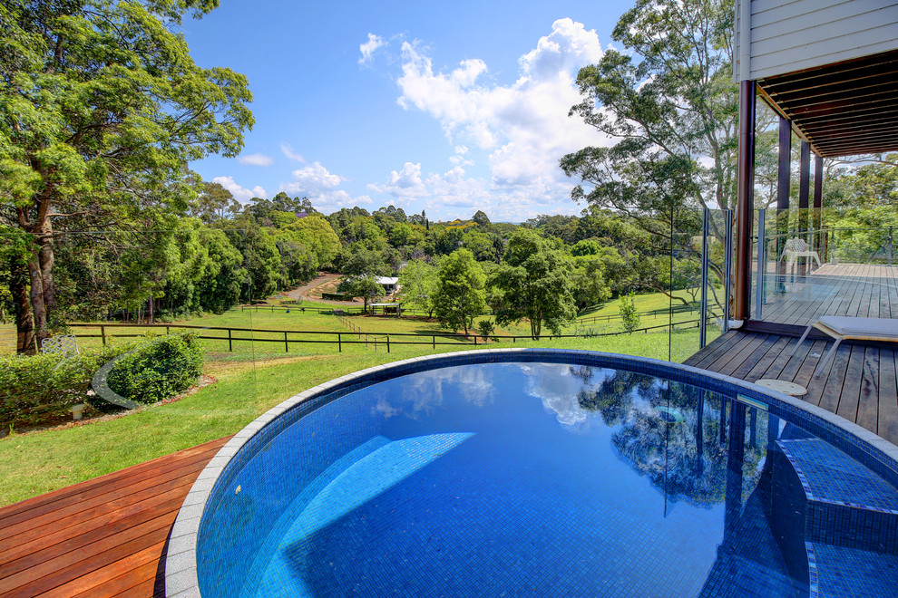 Réalisation d'une piscine hors-sol et arrière champêtre de taille moyenne et ronde avec du carrelage.