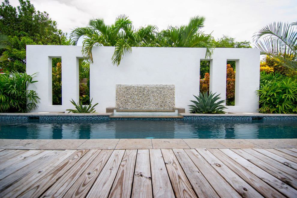 Foto di una piscina tropicale rettangolare di medie dimensioni e dietro casa con fontane e pedane