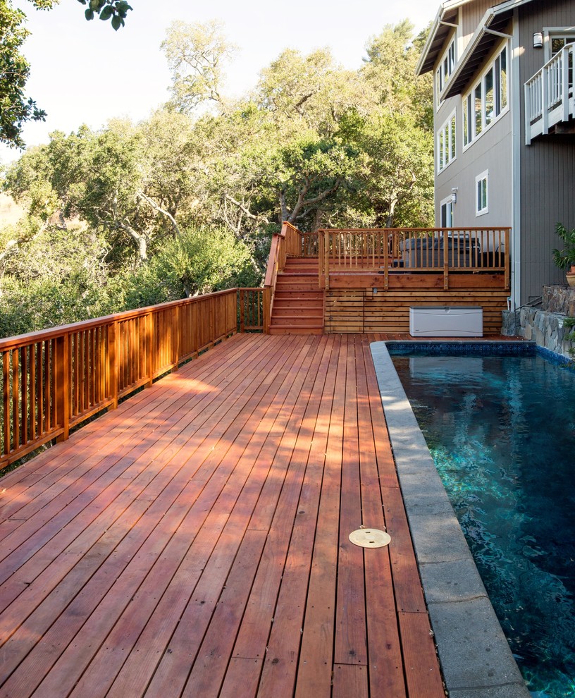 Diseño de piscina alargada clásica grande a medida en patio trasero con entablado