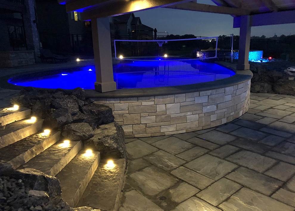 Inspiration for a back custom shaped swimming pool in Omaha with a pool house and natural stone paving.