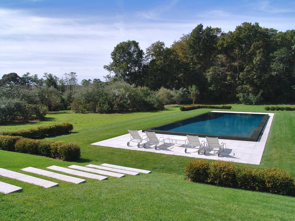 Aménagement d'une piscine arrière contemporaine rectangle avec des pavés en pierre naturelle.