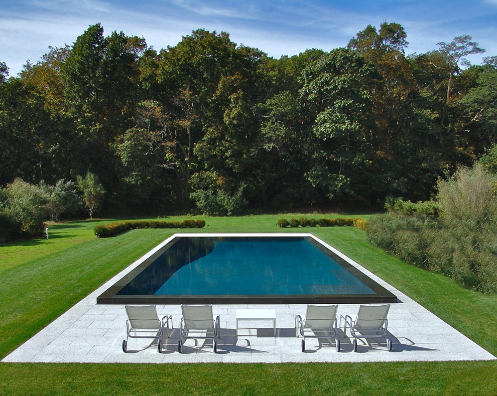 Esempio di una piscina a sfioro infinito minimalista rettangolare di medie dimensioni e dietro casa con pavimentazioni in pietra naturale