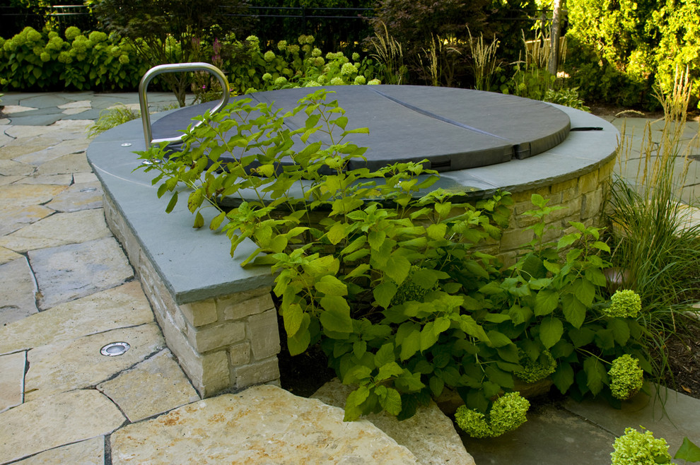 Idee per una piscina fuori terra classica rotonda dietro casa con una vasca idromassaggio e pavimentazioni in pietra naturale