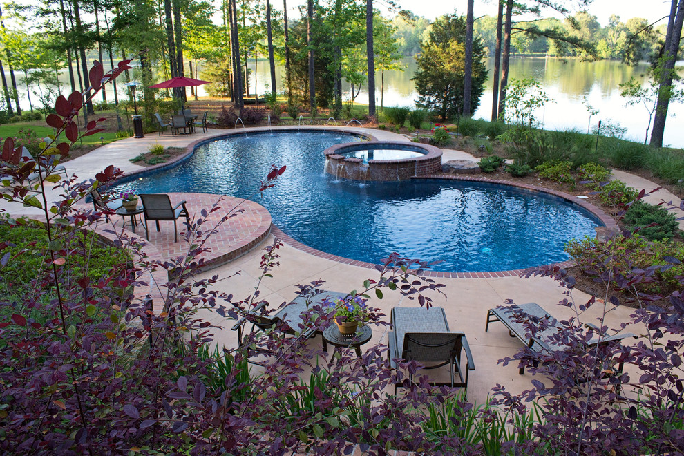 Foto de piscinas y jacuzzis alargados clásicos grandes a medida en patio trasero con adoquines de ladrillo