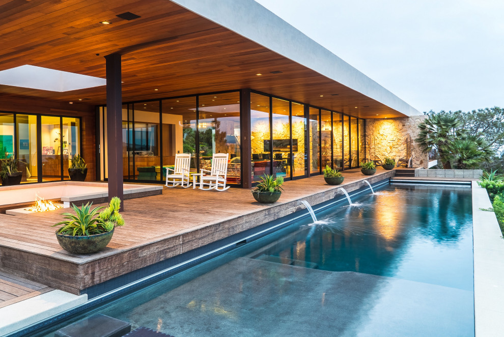 Immagine di una grande piscina minimal rettangolare dietro casa con pedane e fontane