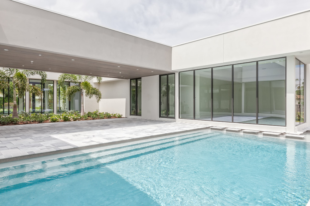 Immagine di una grande piscina monocorsia moderna rettangolare dietro casa con piastrelle