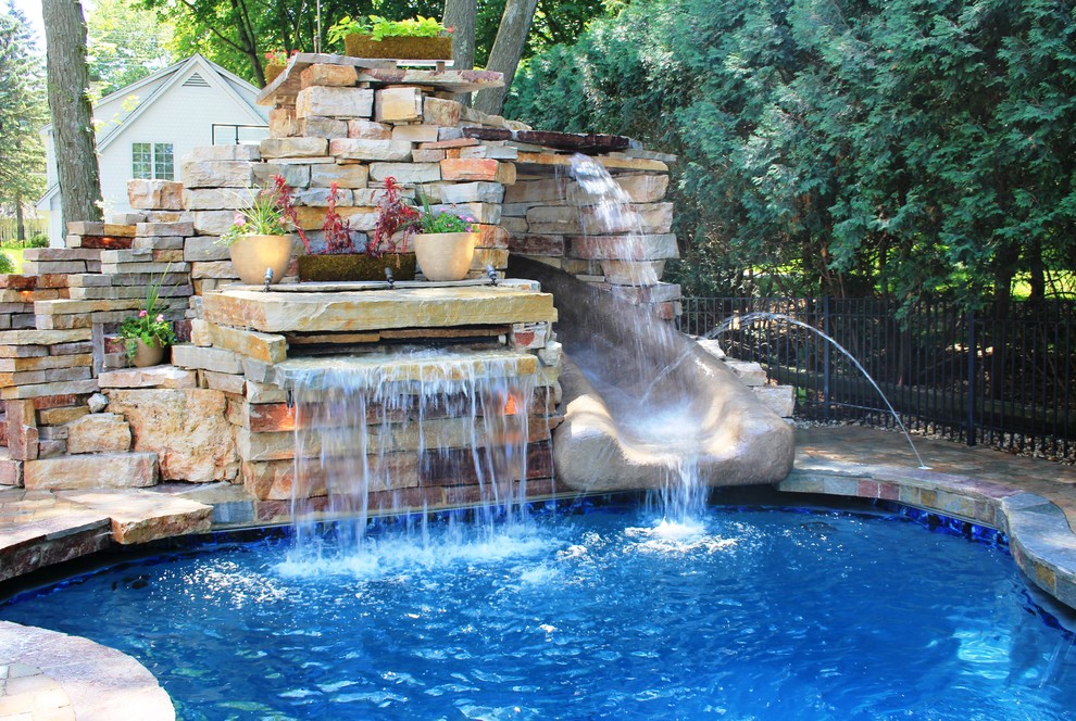 На фото: естественный бассейн среднего размера, произвольной формы на заднем дворе в стиле фьюжн с водной горкой и мощением тротуарной плиткой с