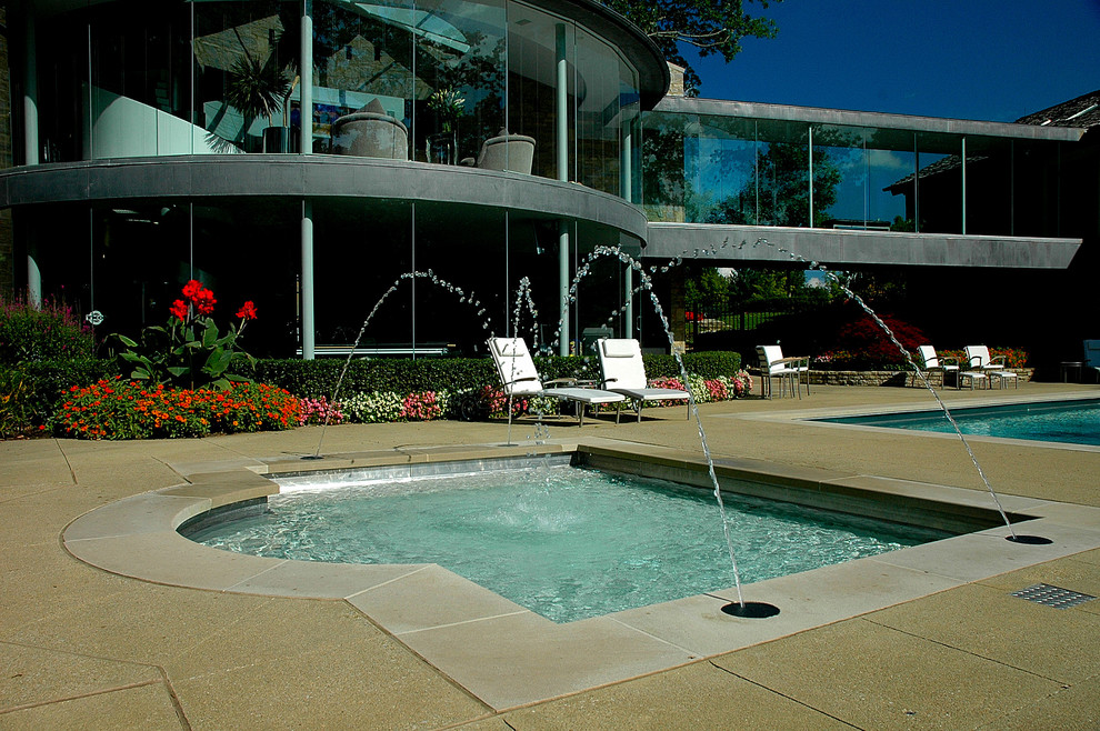 Modern inredning av en anpassad pool på baksidan av huset, med en fontän och trädäck