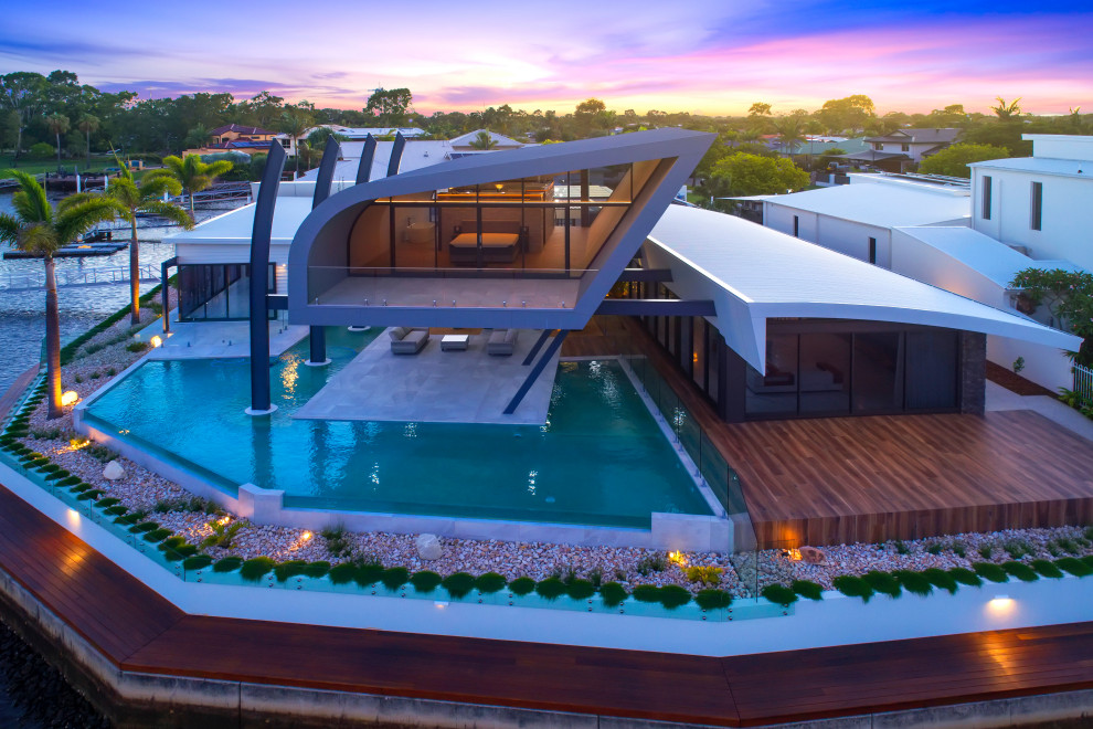 Immagine di un'ampia piscina a sfioro infinito contemporanea personalizzata dietro casa con piastrelle
