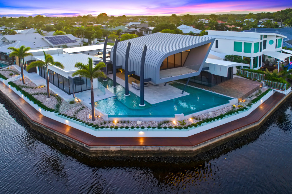 Immagine di un'ampia piscina a sfioro infinito design personalizzata dietro casa con piastrelle