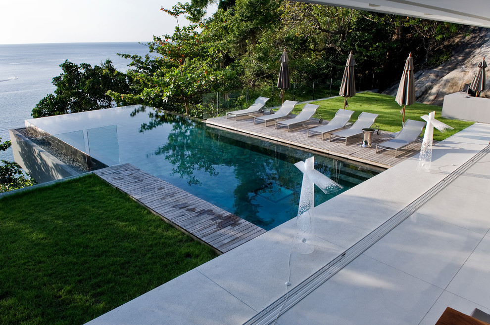 Diseño de piscina infinita minimalista grande rectangular en patio trasero con entablado