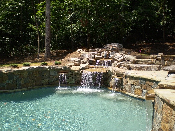 Klassischer Schwimmteich hinter dem Haus in individueller Form mit Natursteinplatten in Sonstige