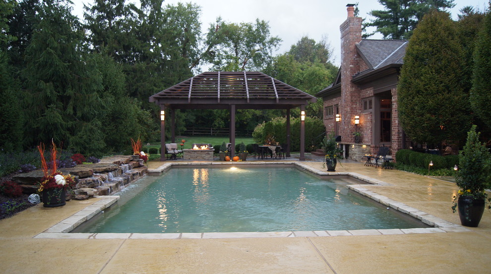 Ispirazione per una grande piscina tradizionale rettangolare dietro casa con fontane e cemento stampato