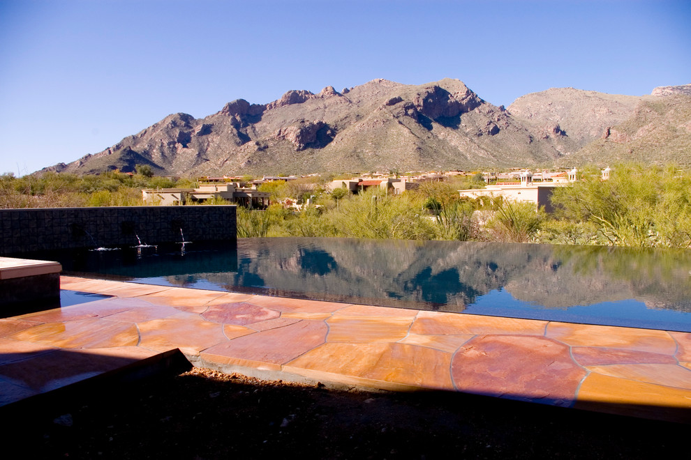 Ejemplo de piscina con fuente infinita actual grande a medida en patio trasero con suelo de baldosas