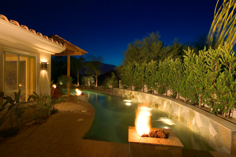 Imagen de piscina con fuente alargada tradicional renovada grande en forma de L en patio trasero con adoquines de ladrillo