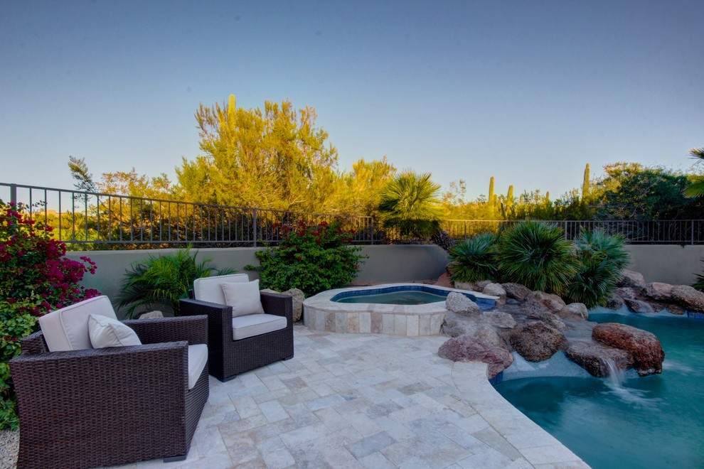 Design ideas for a large back custom shaped natural swimming pool in Phoenix with a water feature and natural stone paving.