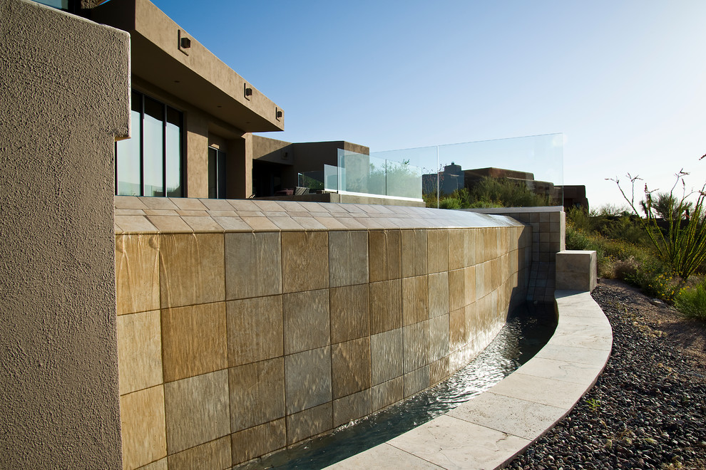 На фото: бассейн-инфинити произвольной формы, среднего размера на заднем дворе в современном стиле с покрытием из каменной брусчатки и фонтаном
