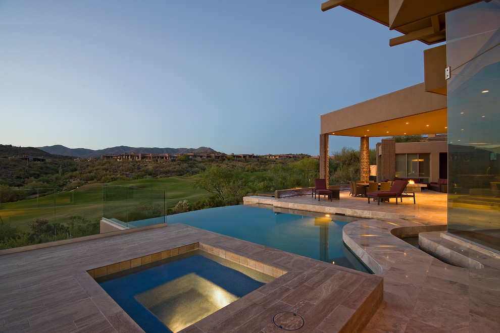 Immagine di una piscina a sfioro infinito minimal personalizzata dietro casa e di medie dimensioni con fontane e pavimentazioni in pietra naturale