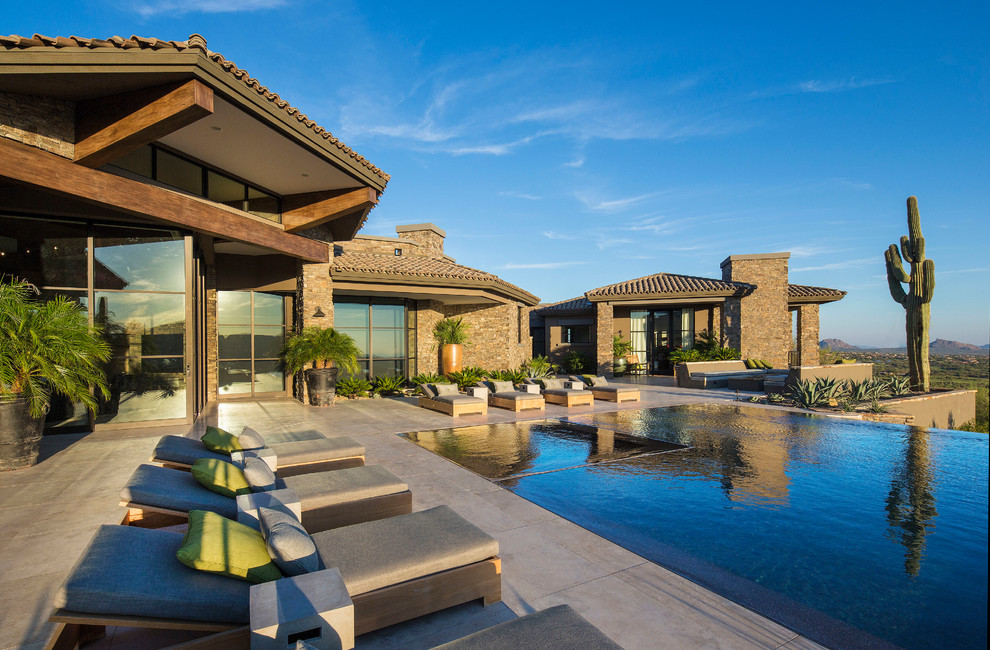 Example of a huge trendy backyard stone and custom-shaped infinity hot tub design in Phoenix
