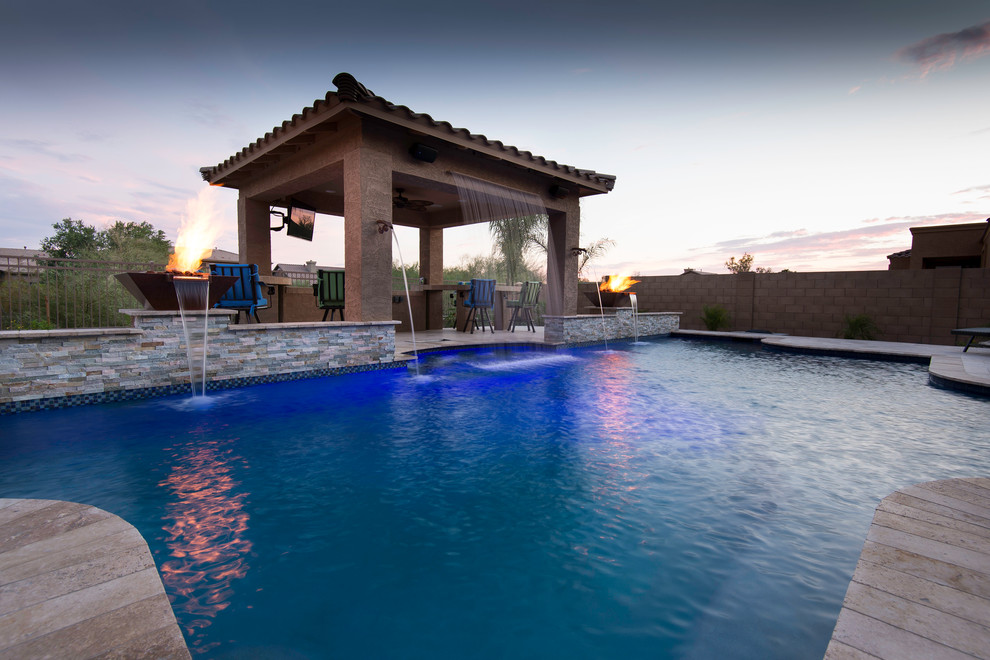 Immagine di una grande piscina mediterranea personalizzata dietro casa con fontane e pavimentazioni in pietra naturale