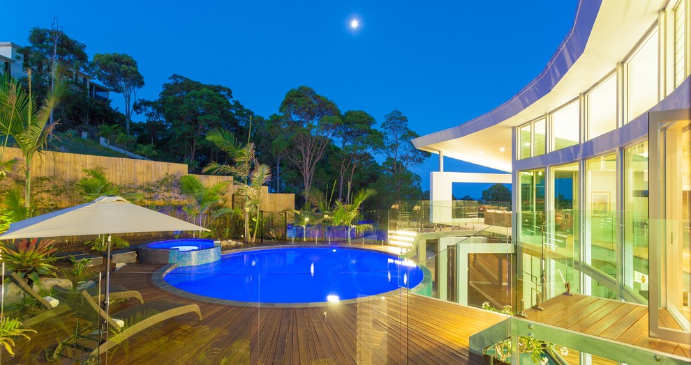 Foto de piscinas y jacuzzis infinitos minimalistas grandes redondeados en patio trasero con entablado