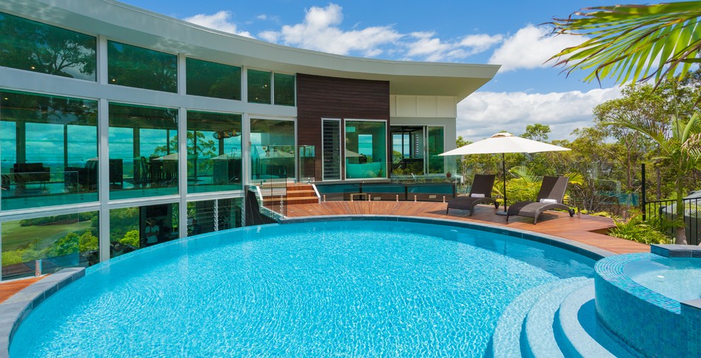 Foto de piscinas y jacuzzis infinitos modernos grandes redondeados en patio trasero con entablado