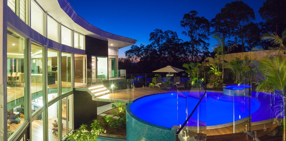 Idee per una grande piscina a sfioro infinito minimalista rotonda dietro casa con fontane e pedane