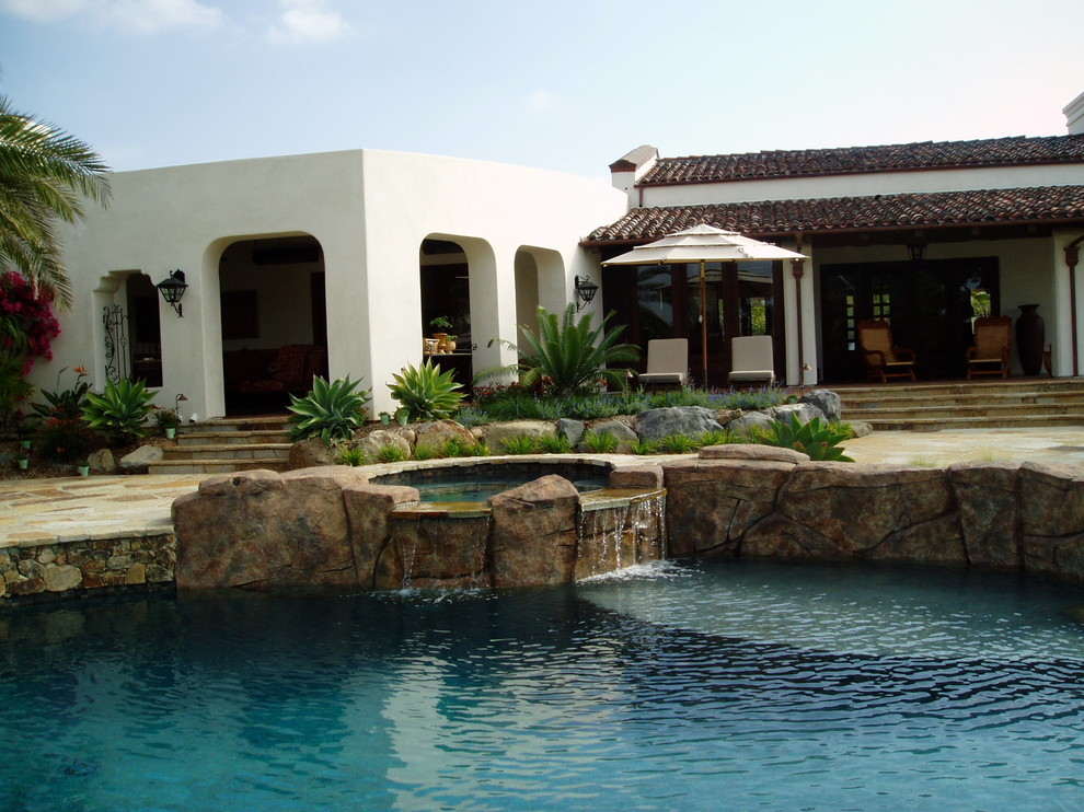 Foto di una piscina naturale mediterranea personalizzata di medie dimensioni e dietro casa con una vasca idromassaggio e pavimentazioni in pietra naturale