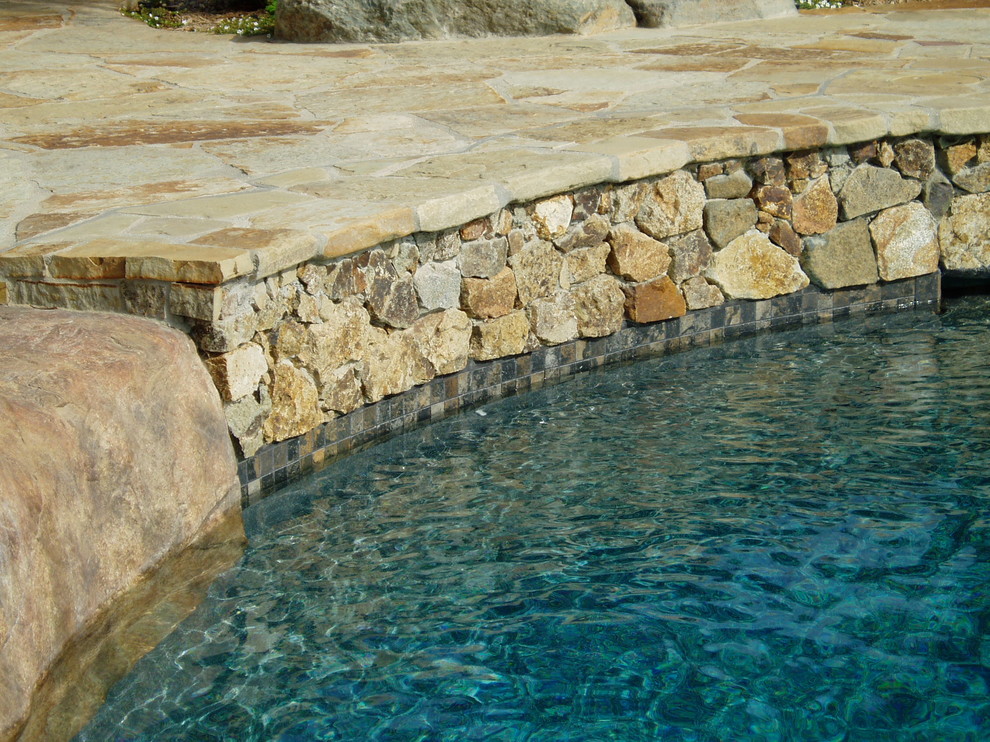 Идея дизайна: большой естественный бассейн в форме фасоли на заднем дворе в средиземноморском стиле с джакузи и покрытием из каменной брусчатки
