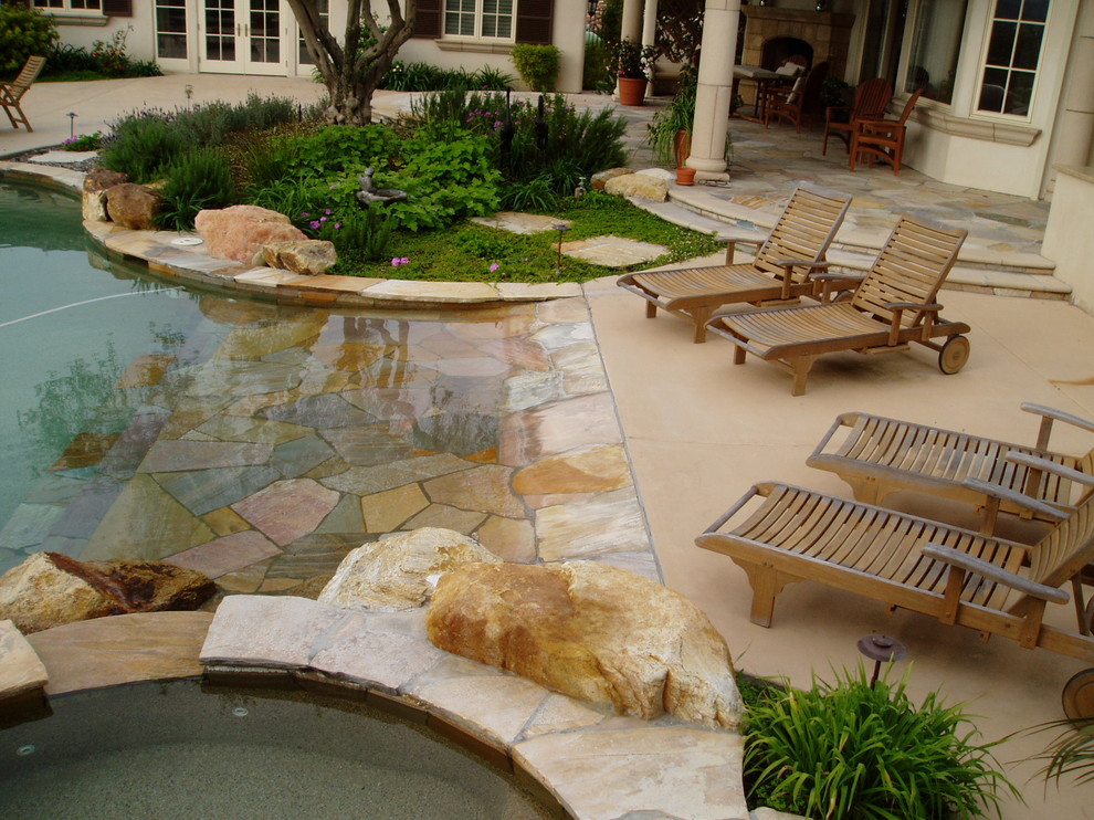 Immagine di una grande piscina mediterranea personalizzata dietro casa con una vasca idromassaggio e pavimentazioni in pietra naturale