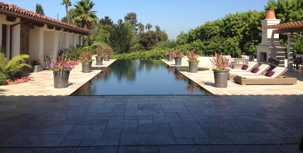 Geräumiger Mediterraner Pool hinter dem Haus in rechteckiger Form mit Natursteinplatten in San Diego