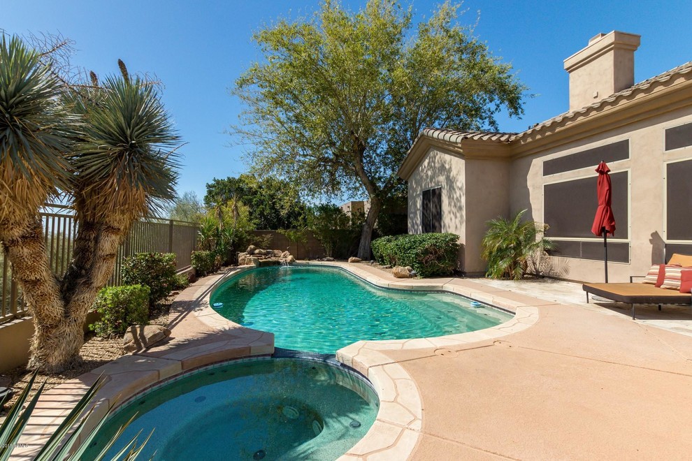 Immagine di una piscina stile americano a "C" di medie dimensioni e dietro casa con una vasca idromassaggio