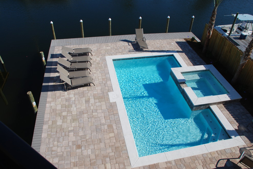 Immagine di una grande piscina monocorsia chic rettangolare dietro casa con una vasca idromassaggio e pavimentazioni in pietra naturale