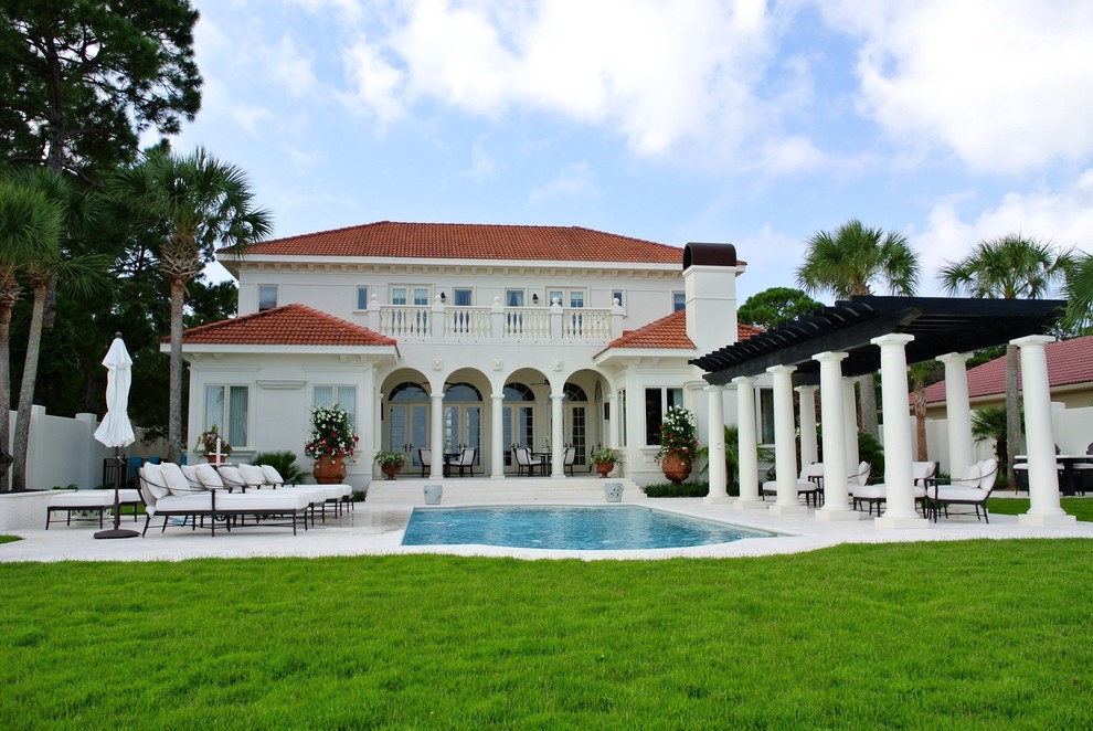 Large mediterranean back custom shaped lengths swimming pool in Miami with natural stone paving and a water feature.