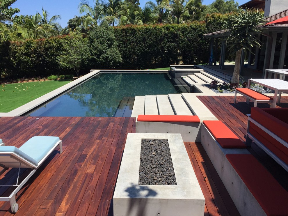 Foto de piscina actual grande rectangular en patio trasero con losas de hormigón