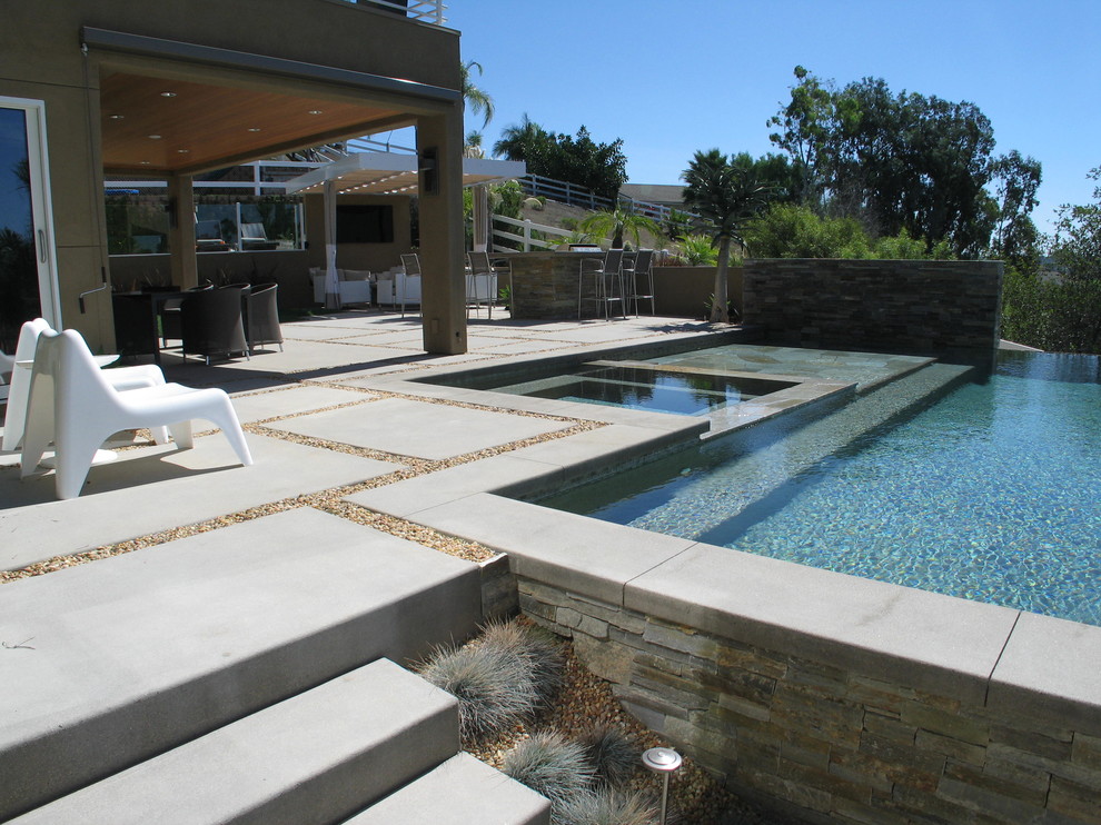 Inspiration for a large modern backyard concrete and rectangular infinity pool remodel in San Diego