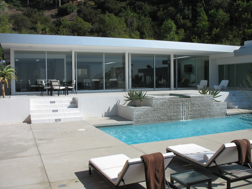 Diseño de piscina con fuente moderna rectangular con suelo de hormigón estampado