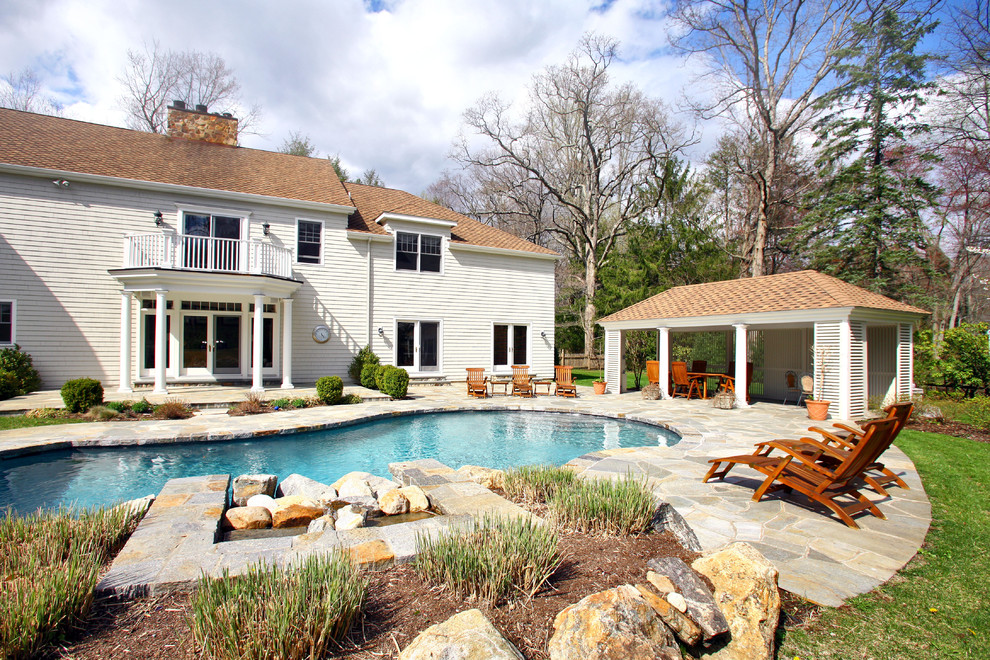Пример оригинального дизайна: бассейн в форме фасоли на заднем дворе в классическом стиле с покрытием из каменной брусчатки