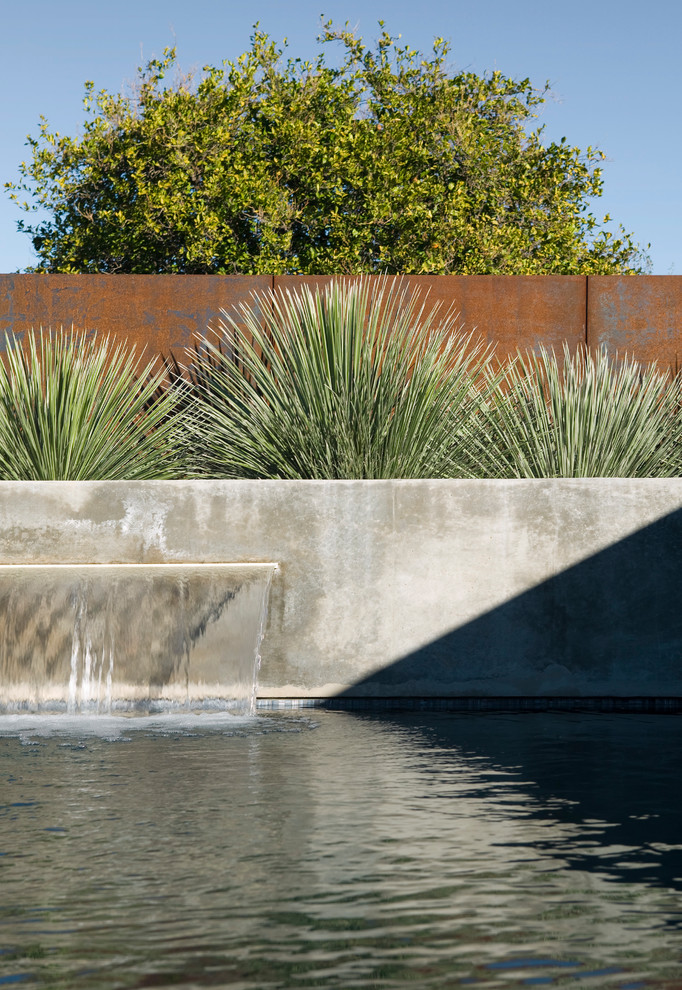 Diseño de piscina con fuente minimalista de tamaño medio rectangular en patio con losas de hormigón