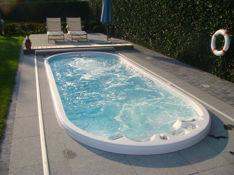 Aménagement d'une piscine hors-sol classique de taille moyenne et sur mesure avec des pavés en béton.
