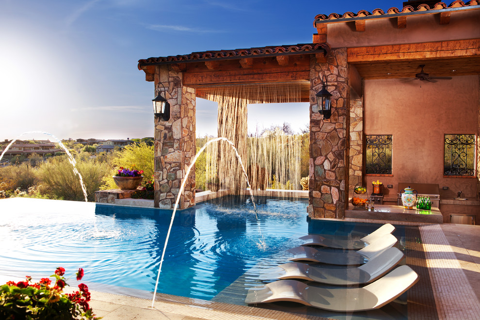Immagine di un'ampia piscina a sfioro infinito mediterranea personalizzata dietro casa con fontane e piastrelle