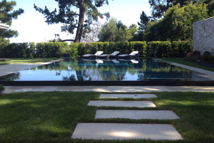 На фото: прямоугольный бассейн среднего размера на заднем дворе в современном стиле с покрытием из бетонных плит